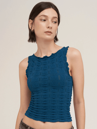 A woman wearing a sleeveless textured floral edge cami  in a deep sea blue,