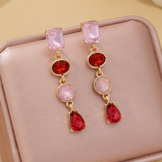 A pair of gold-tone drop earrings with pink and red gemstones.