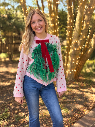 queen of sparkles cardigan. pink with red polka dodts button up with wreath design made up yarn and feathers with a red bow
