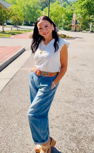 Woman in a white top and barrel babe blue jeans.