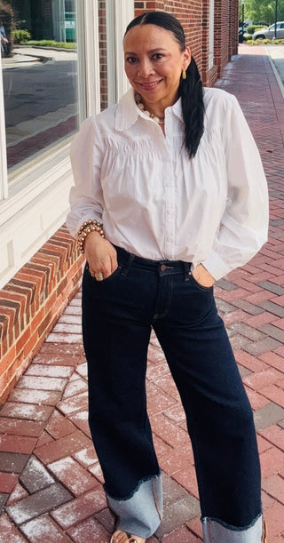 Woman wearing a white blouse and the cool girl cuff denim jeans.