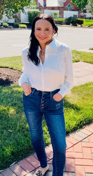 Woman wearing a white blouse and Sage Skinny Jeans. 