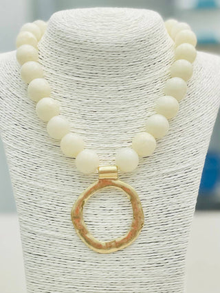 Necklace with white beads and a gold pendant.
