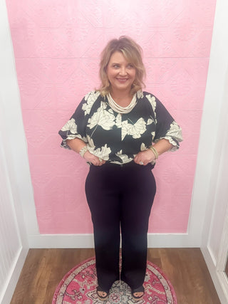 Woman wearing a floral top and stretchy black pants.