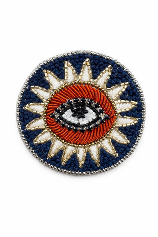 Decorative beaded brooch with sun design and eye symbol.