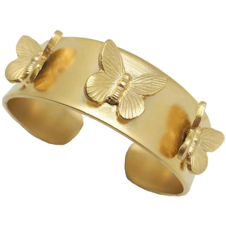 A wide matte gold-tone open cuff bracelet adorned with three raised butterfly motifs featuring detailed engraved wing texture.