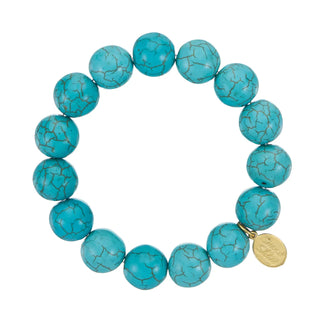 A stretch bracelet composed of large round turquoise beads with brown veining, featuring a small gold-tone branded charm,.