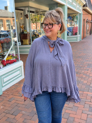 flowy poncho-style blouse, with a self-tie neckline, dramatic wide sleeves, and layered ruffle trim.